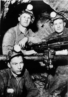 Three men in an underground shaft around a drill, wpH434